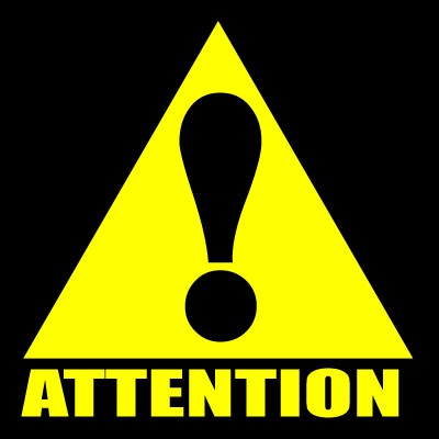 Triangular sign in black and yellow, which has the word attention and an exclamation sign.