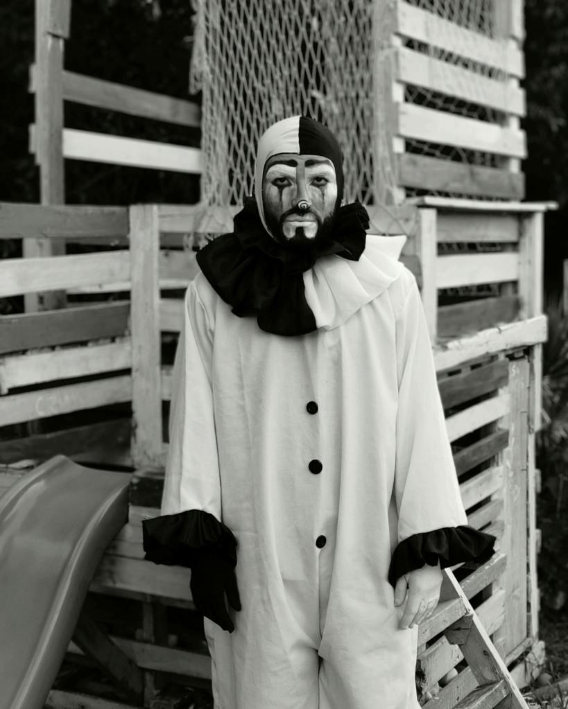 A man dressed in a black and white Pierrot costume